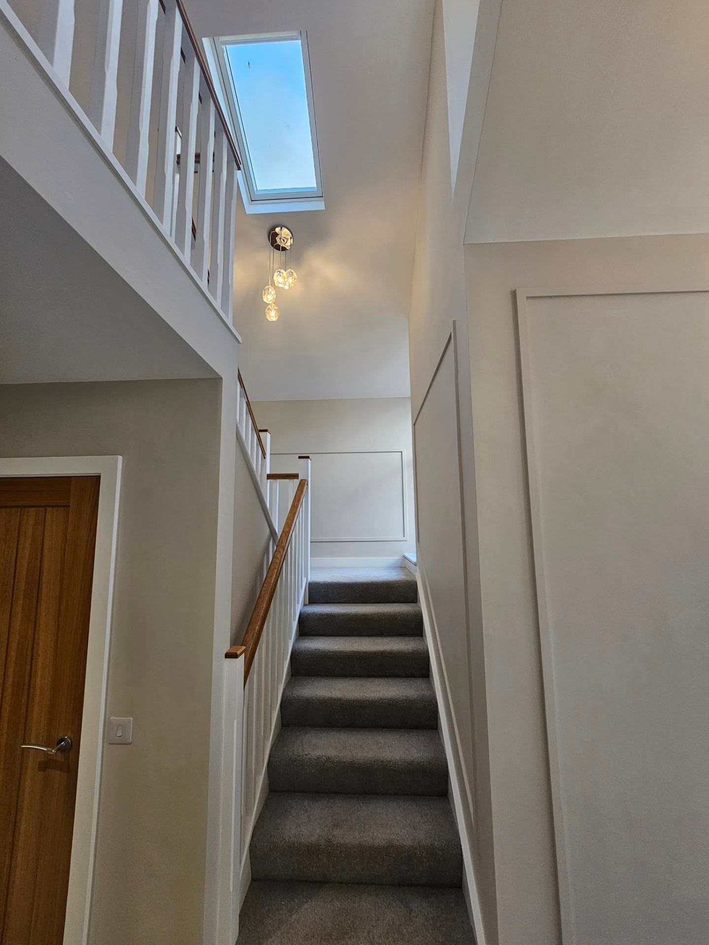 Stairwell with high ceiling, fresh white paint and oak handrail — Cardiff interior painting
