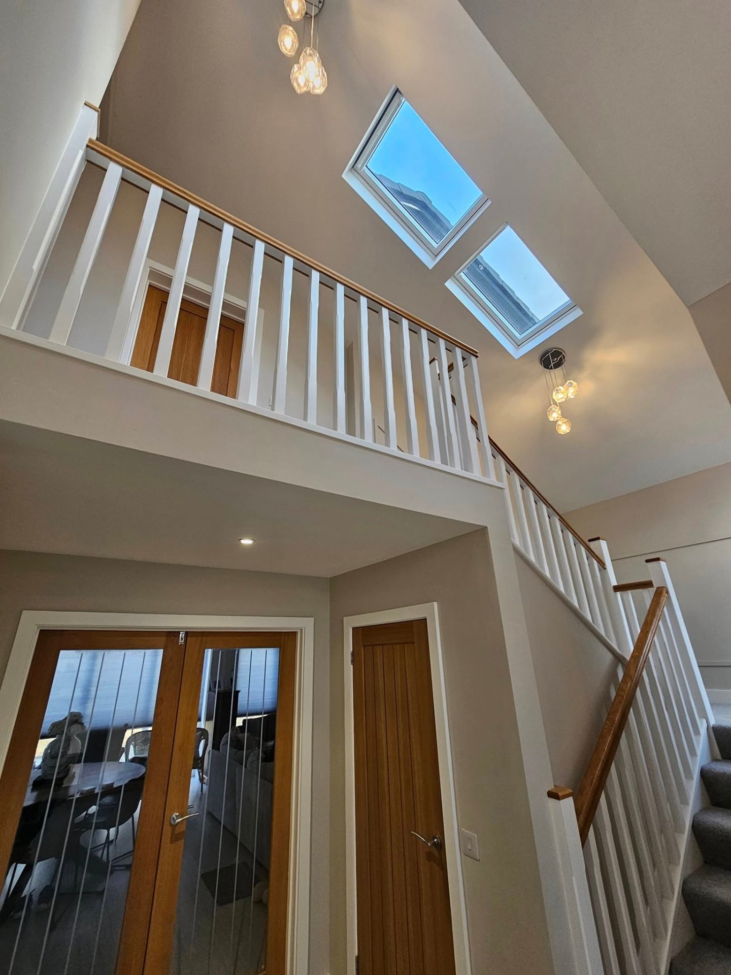 Double-height landing with crisp white spindles and warm neutral walls