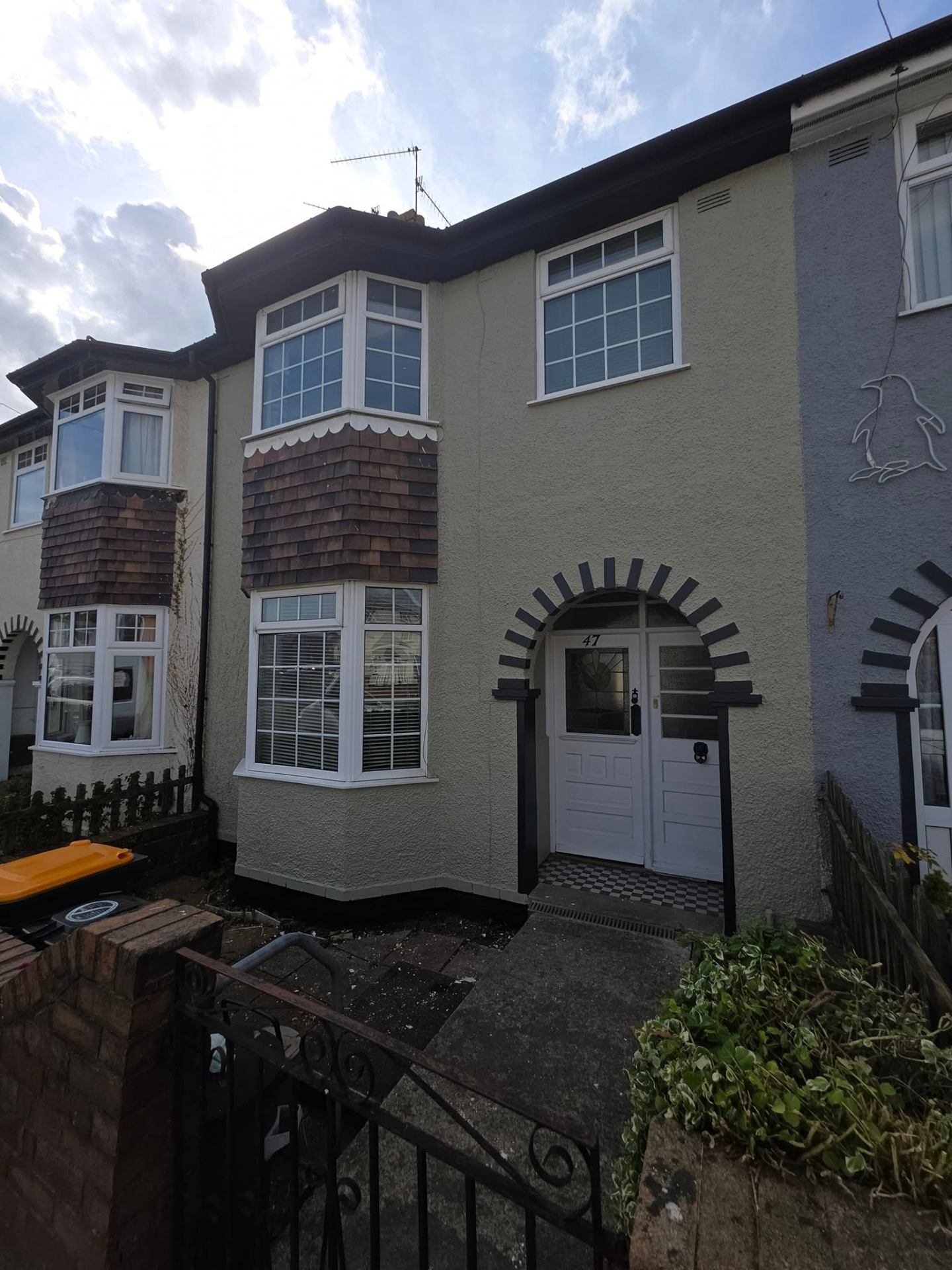Exterior masonry repaint mid-project showing prep, masking and ladder access